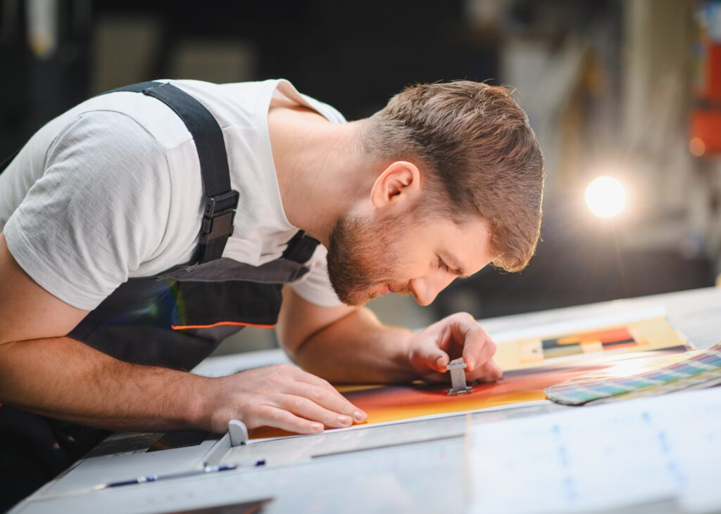 Printing worker checking color palette register on proof sheet