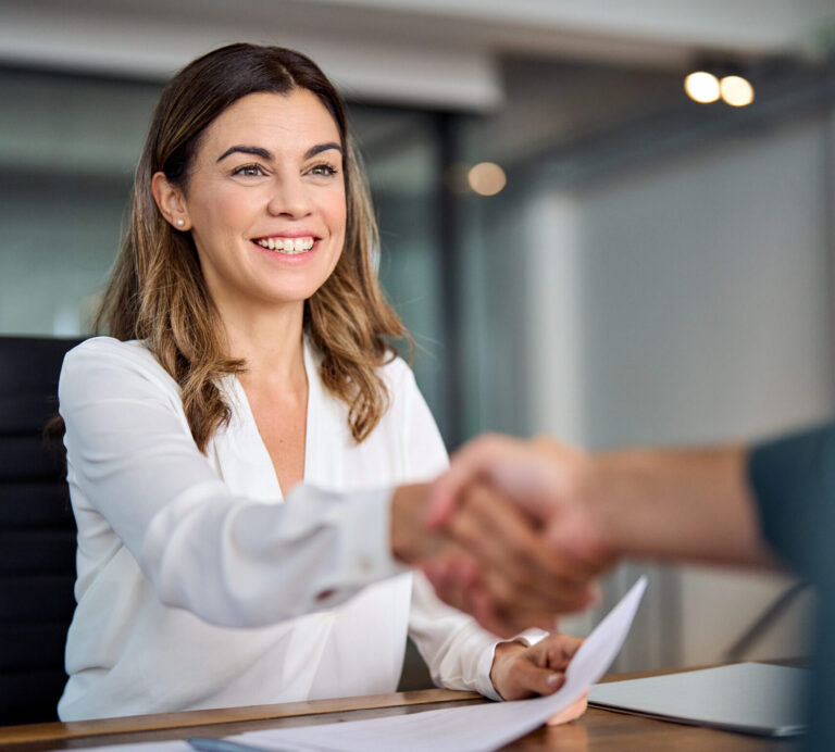 Happy mid aged business woman manager handshaking at office meeting. Smiling female hr hiring recruit at job interview, bank or insurance agent, lawyer making contract deal with client at work.
