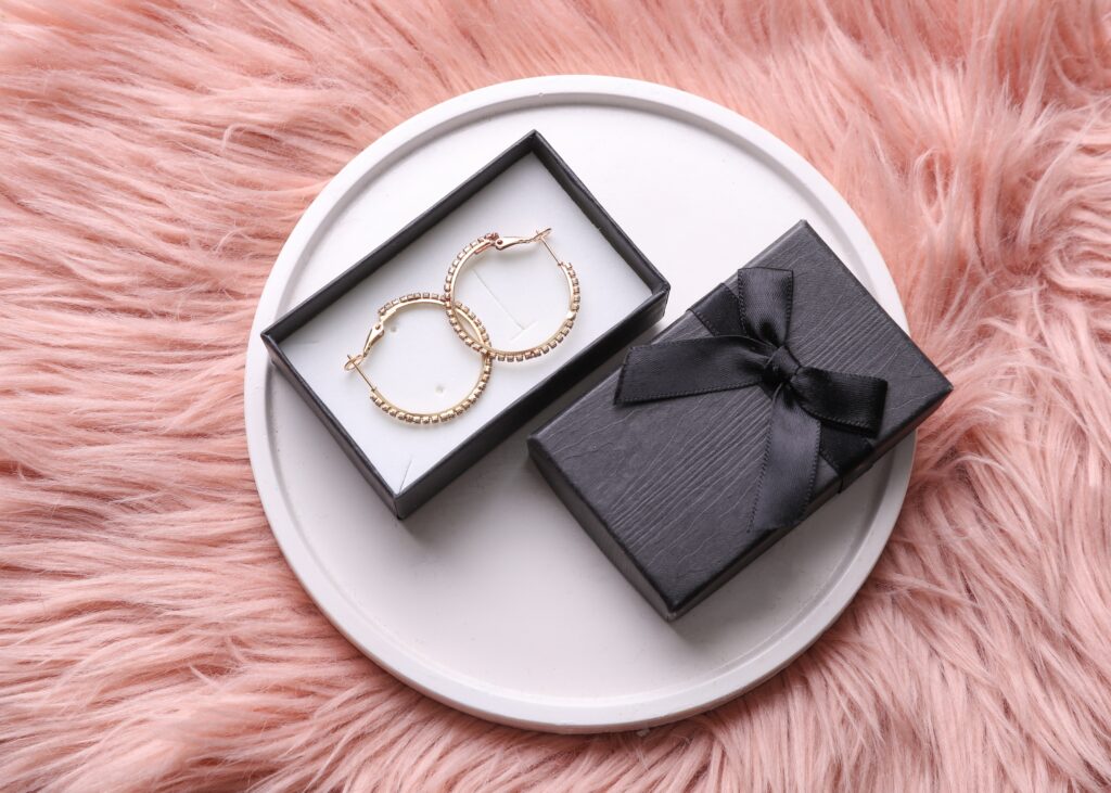 Gold earrings with box on a plaster podium, pink background
