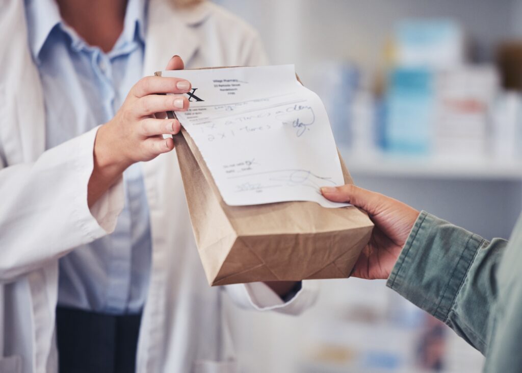 Pharmacy, hands and prescription medicine for customer with paper bag for healthcare, drugs and pharmaceutical. Closeup of a pharmacist or medical worker with person in drugstore for retail service